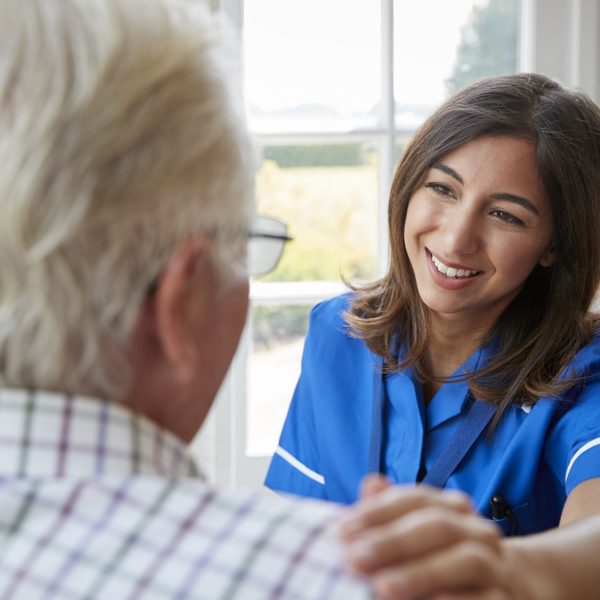 Over shoulder view of nurse on home visit with senior man
