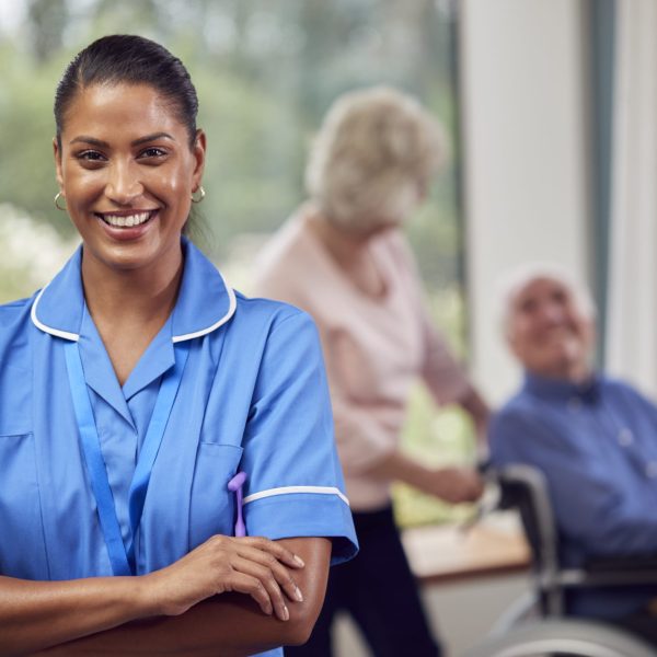 Portrait Of Female Nurse Or Care Worker Making Home Visit To Senior Couple With Man In Wheelchair